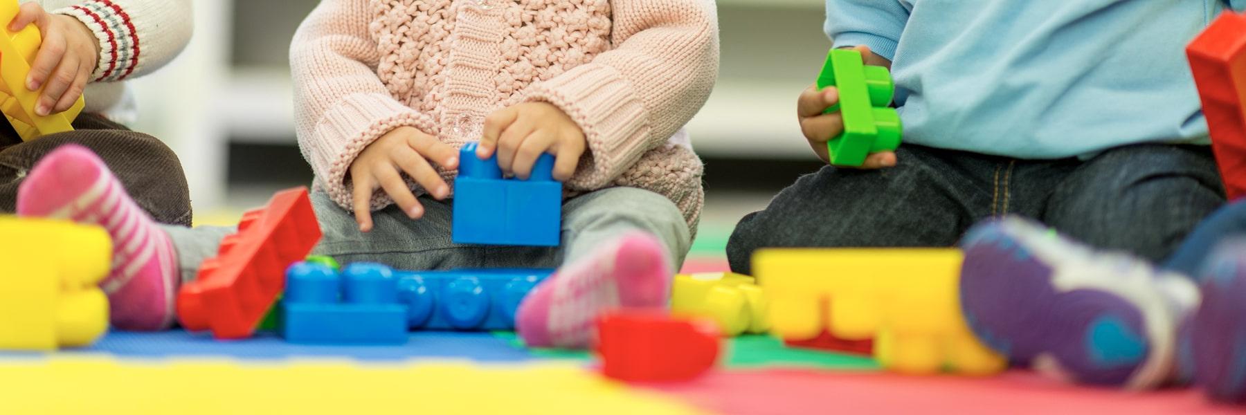 close up of babies from neck down playing with blocks